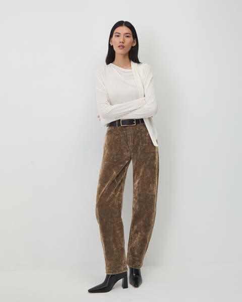 A woman wearing a white top and brown pants.