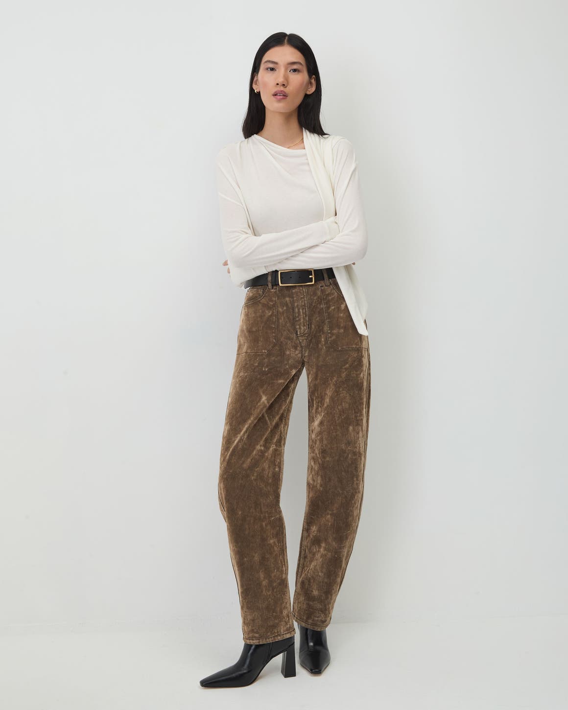 A woman wearing a white top and brown trousers.
