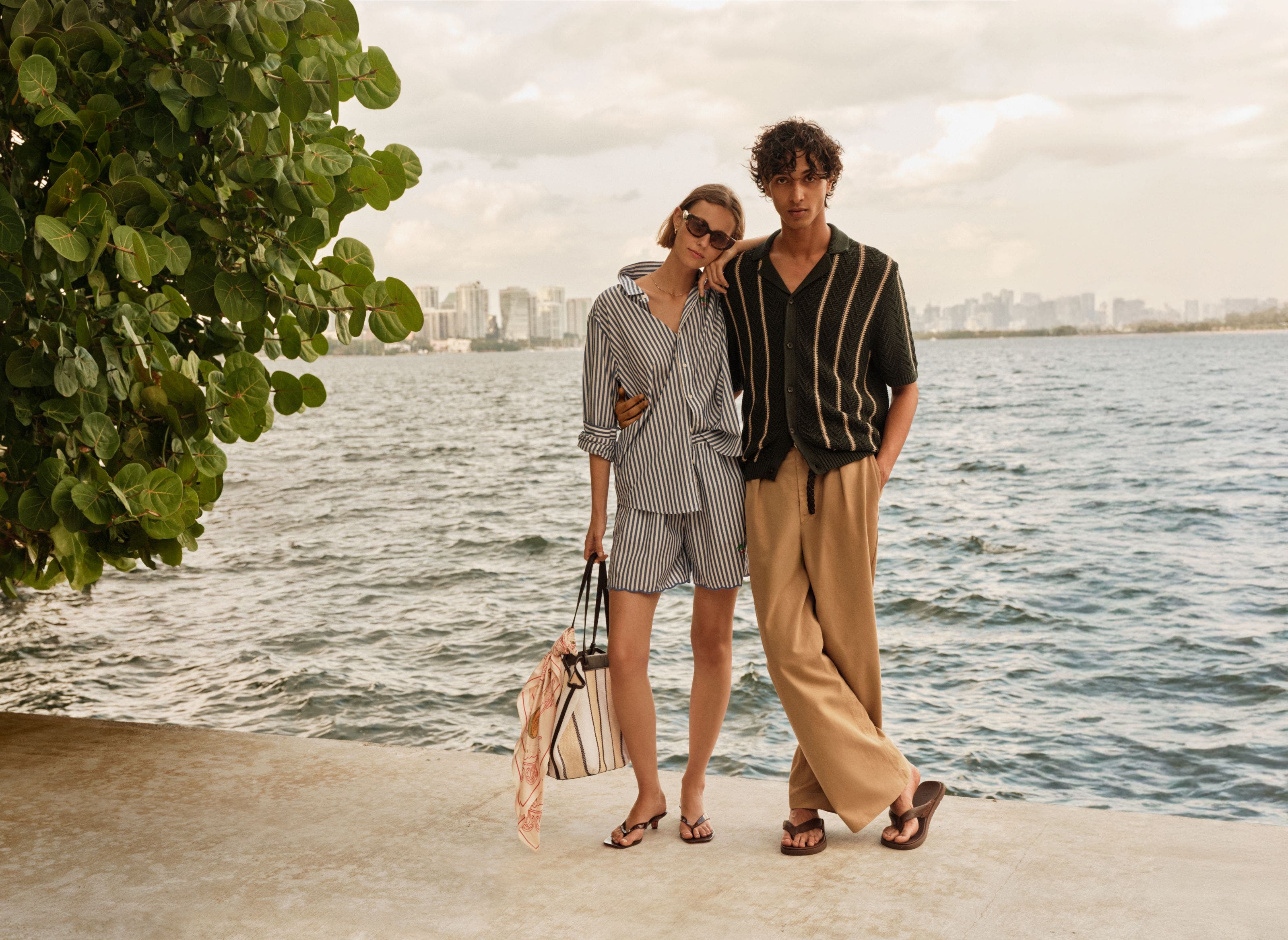 A woman in stripe set and man in stripe polo and pants, both wearing flip flops.