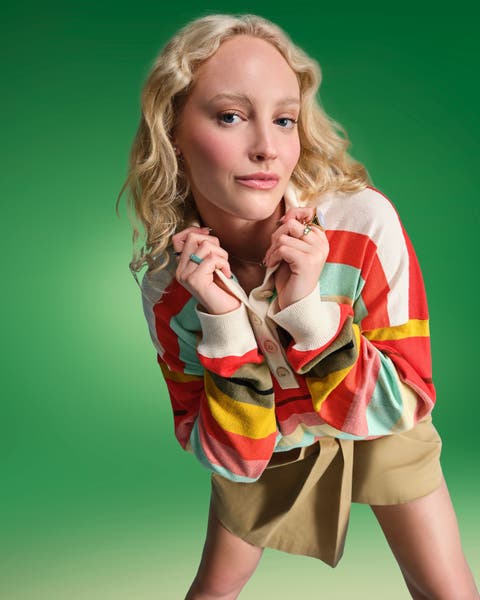 Young woman wearing long sleeve shirt and skirt.