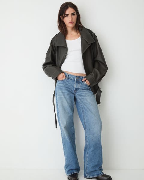 A woman wearing baggy jeans, a white t-shirt, and a leather jacket.