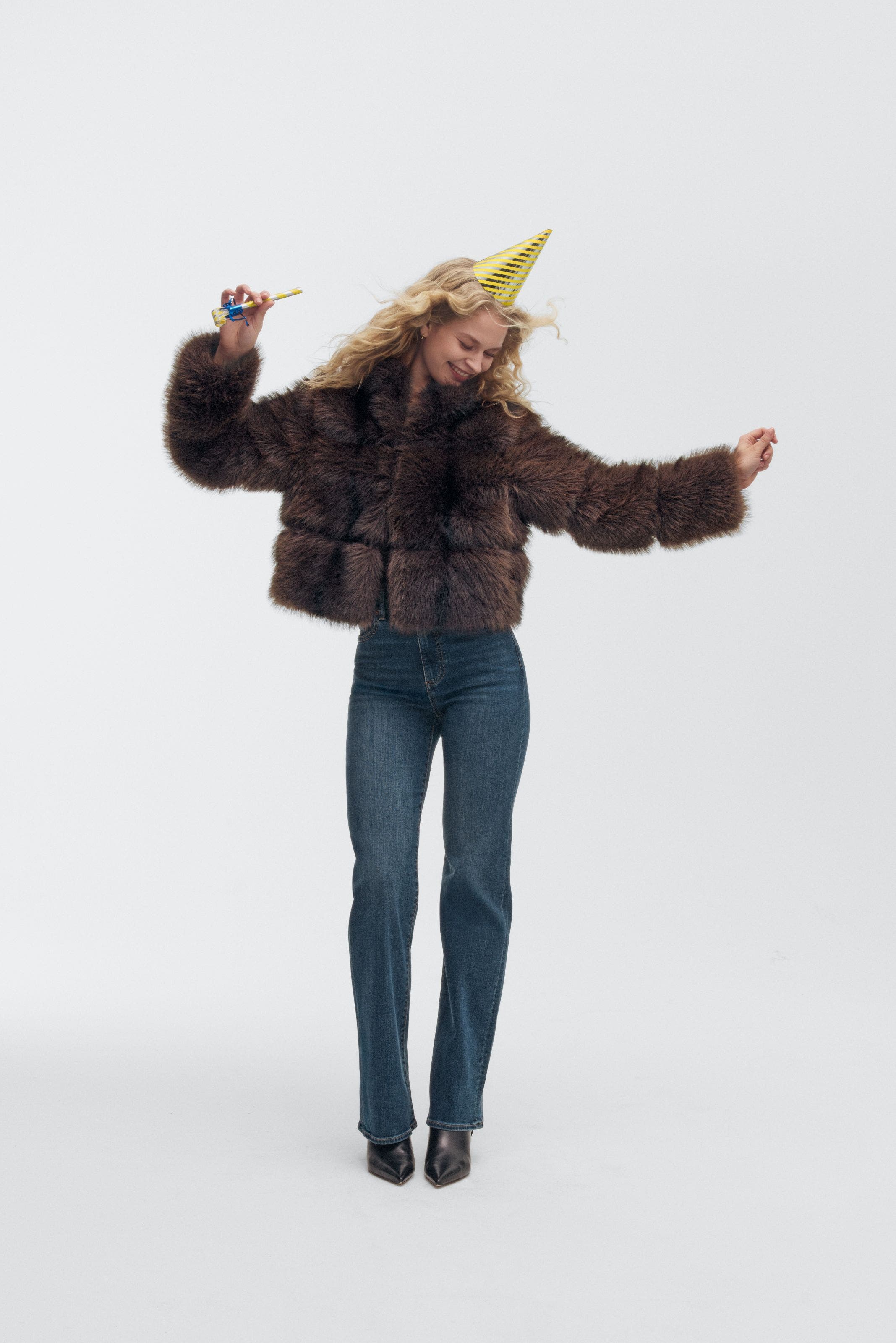 A woman wearing a party hat and faux-fur jacket