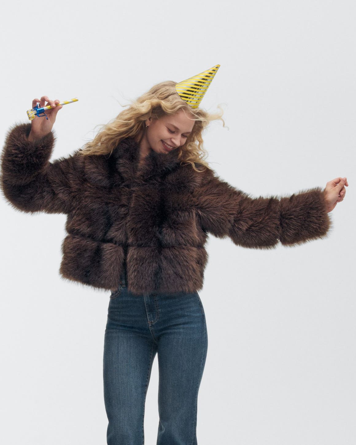 A woman wearing a party hat and faux-fur jacket