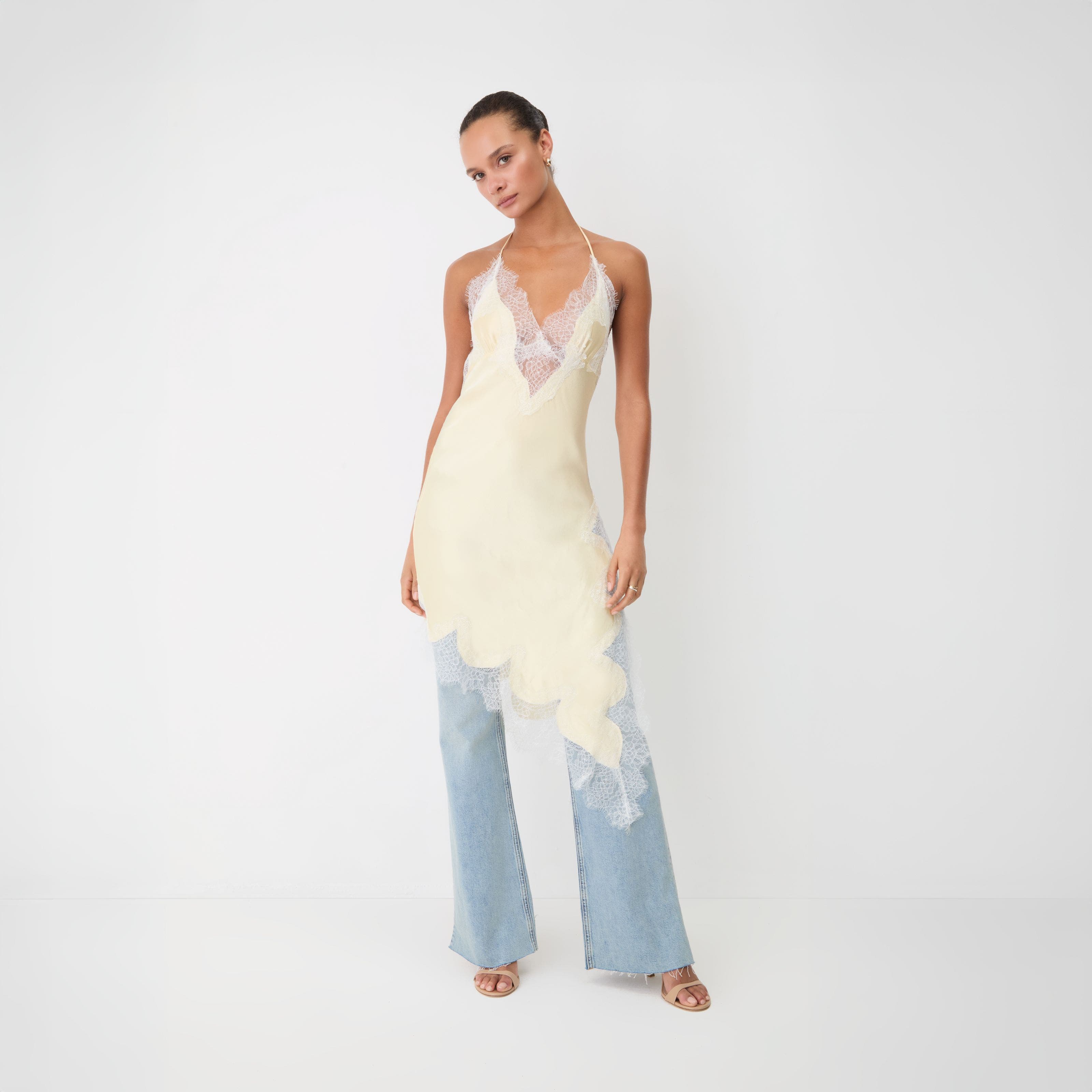 A woman wearing an asymmetrical lace top over a pair of jeans.