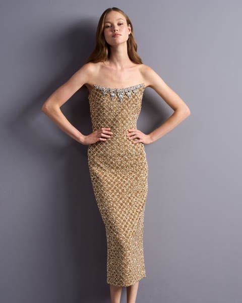 A woman wearing a gold sparkly dress.