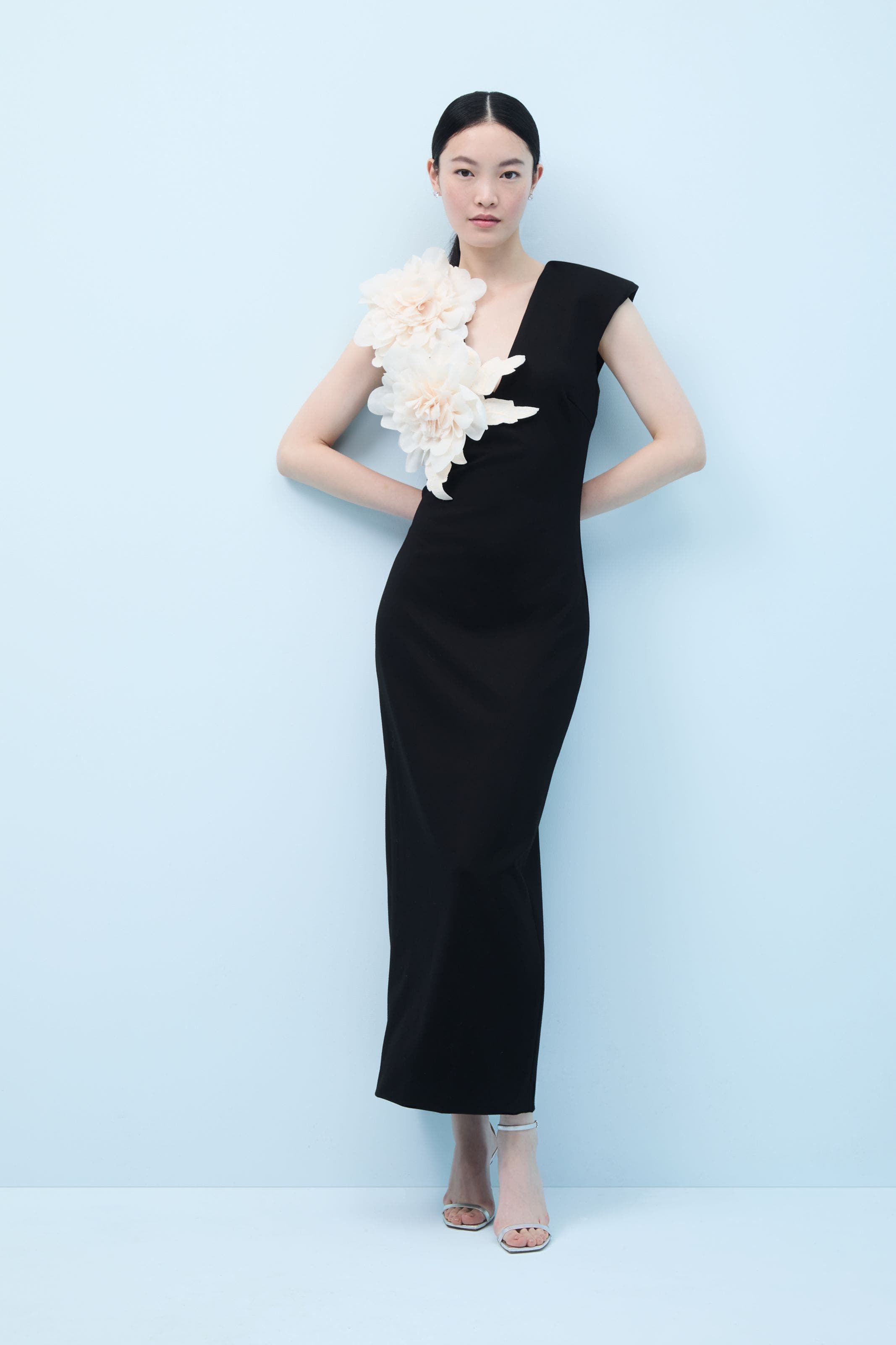 A woman in a black dress embellished with large white flowers.
