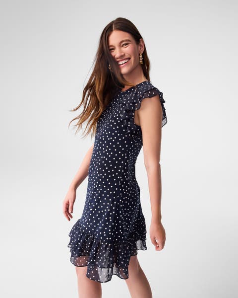 A woman wearing a navy dress with white dots.