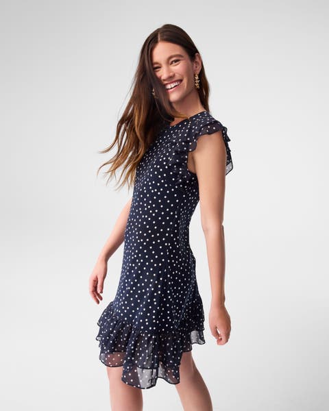 A woman wearing a navy dress with white dots.