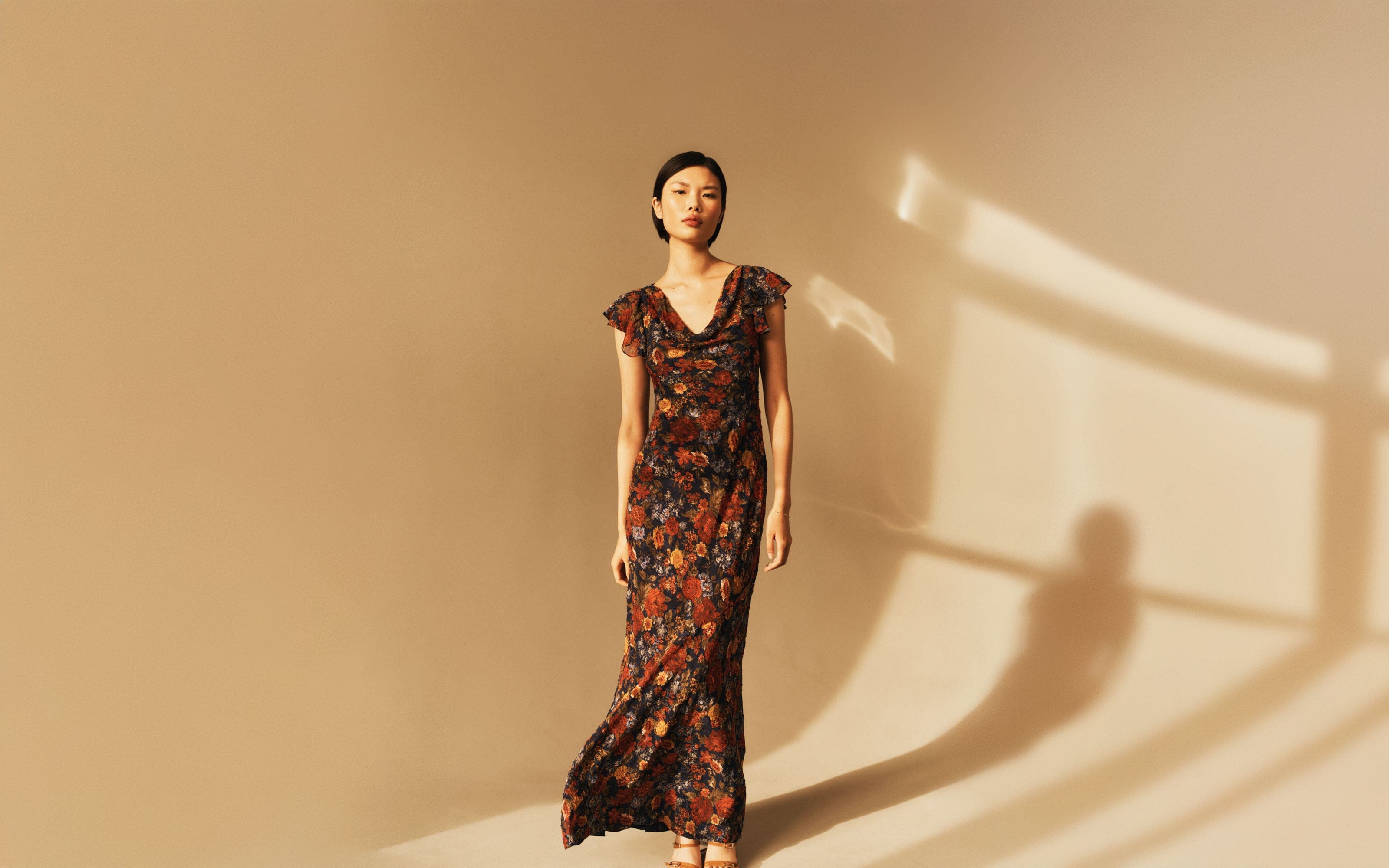 Model wearing a floral gown and heels.