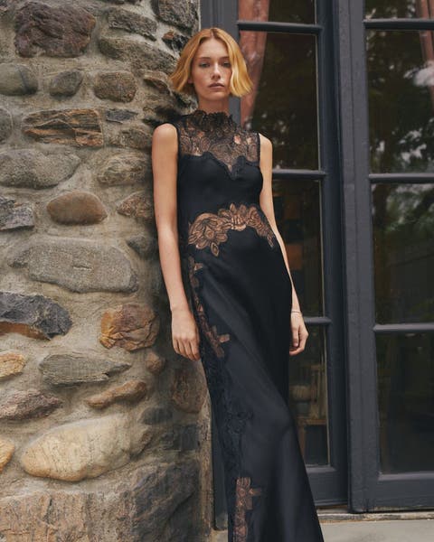 A woman in black gown with sheer lace floral detail.