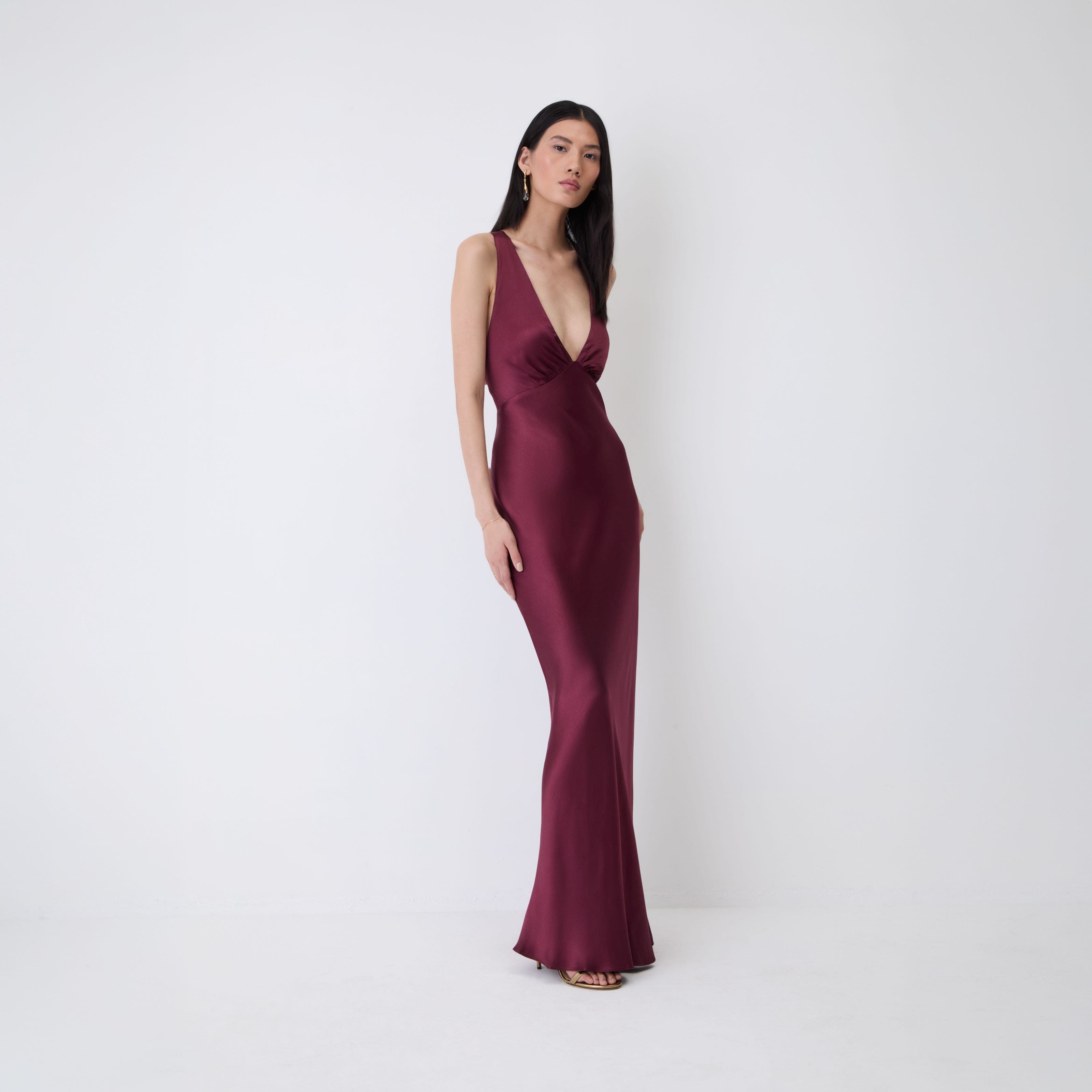 A woman in a burgundy satin slip gown.