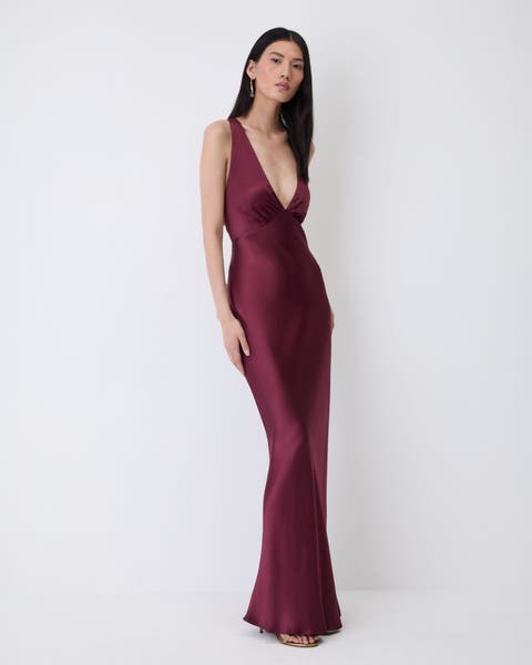 A woman in a burgundy satin slip gown.