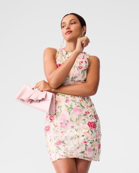 A woman wearing an embroidered floral minidress.