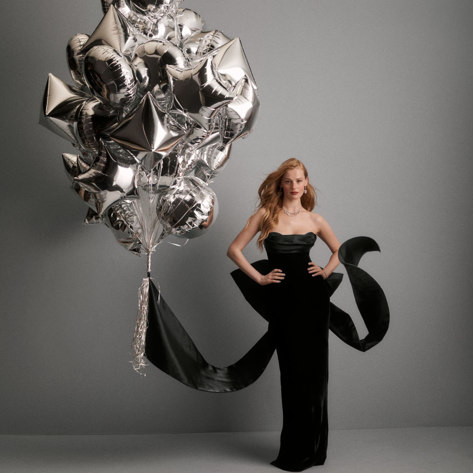 A woman wearing a black gown next to balloons.