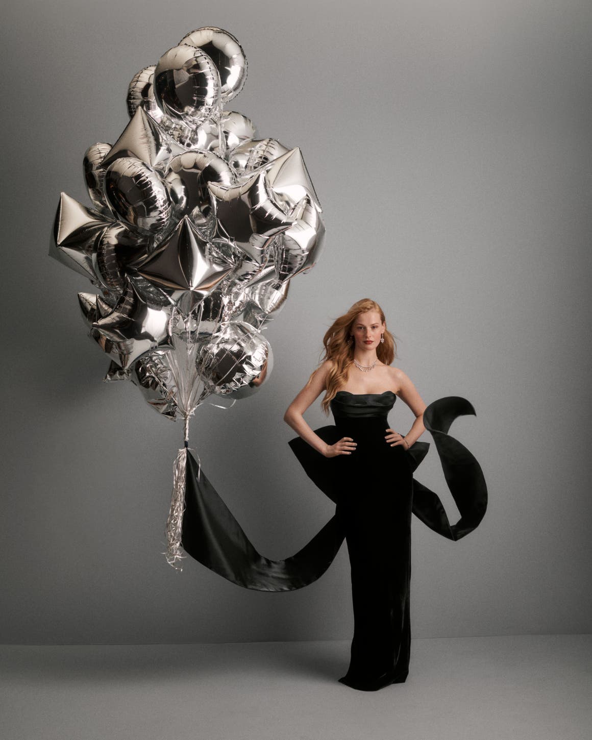 A woman wearing a black gown next to balloons.