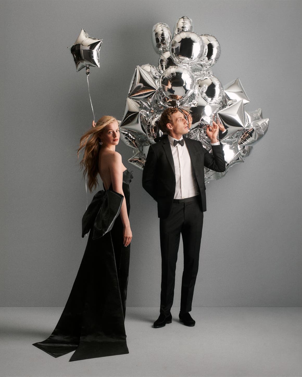 A woman and man in evening wear with balloons.