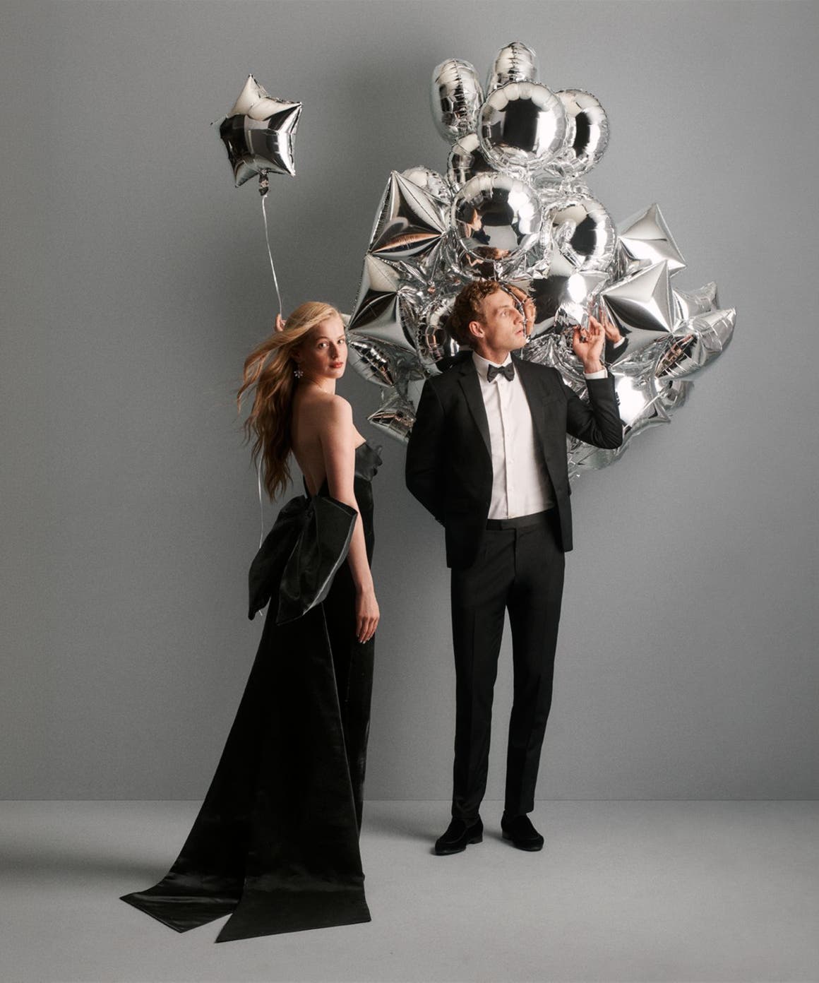 A couple standing next to balloons in holiday dressing.