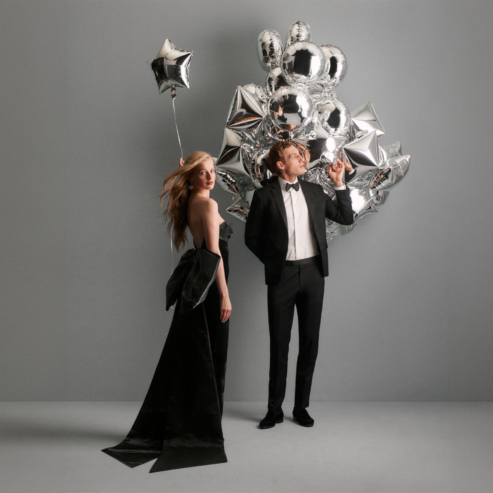 A couple standing next to balloons in holiday dressing.