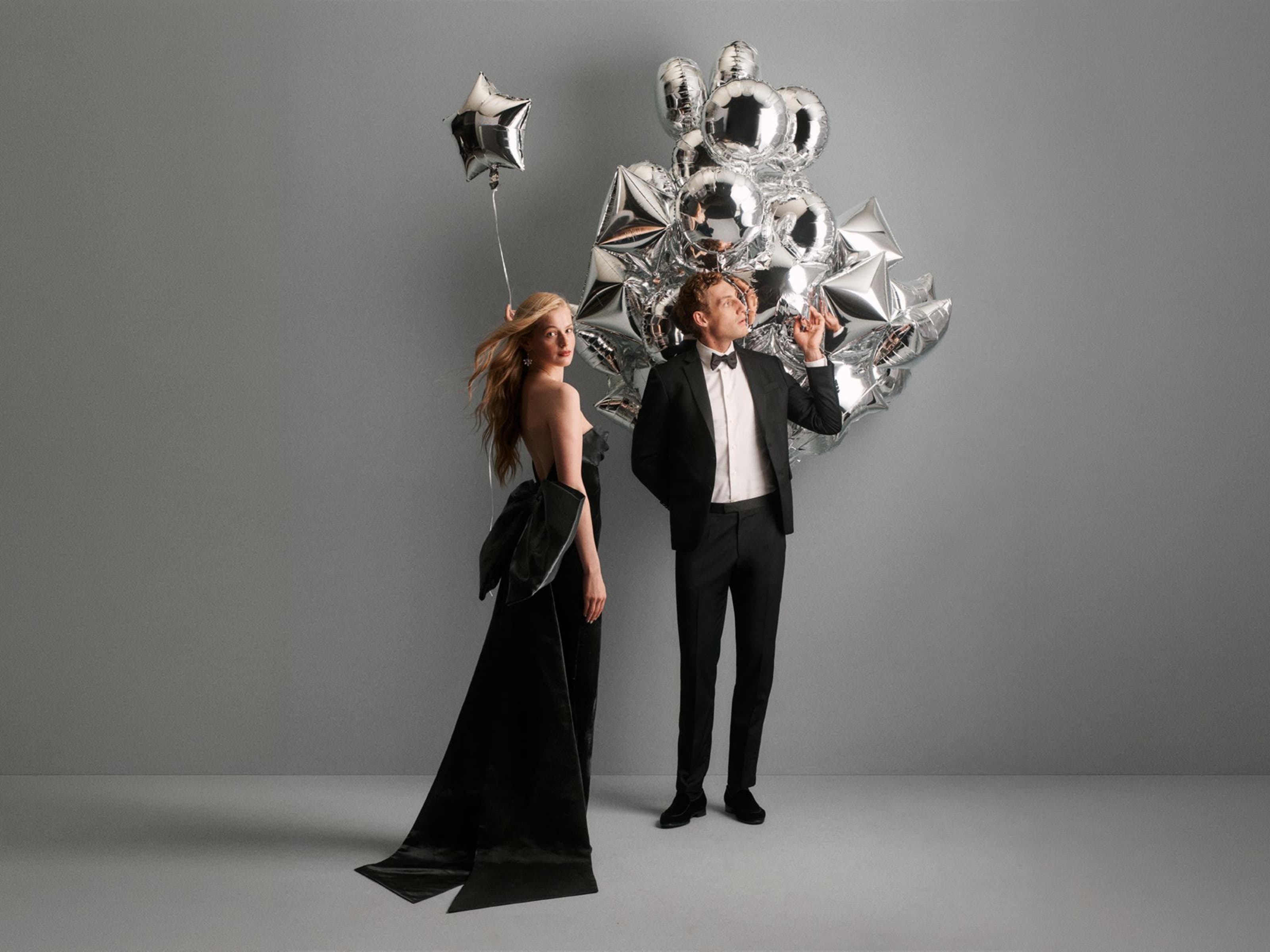 A couple standing next to balloons in holiday dressing.