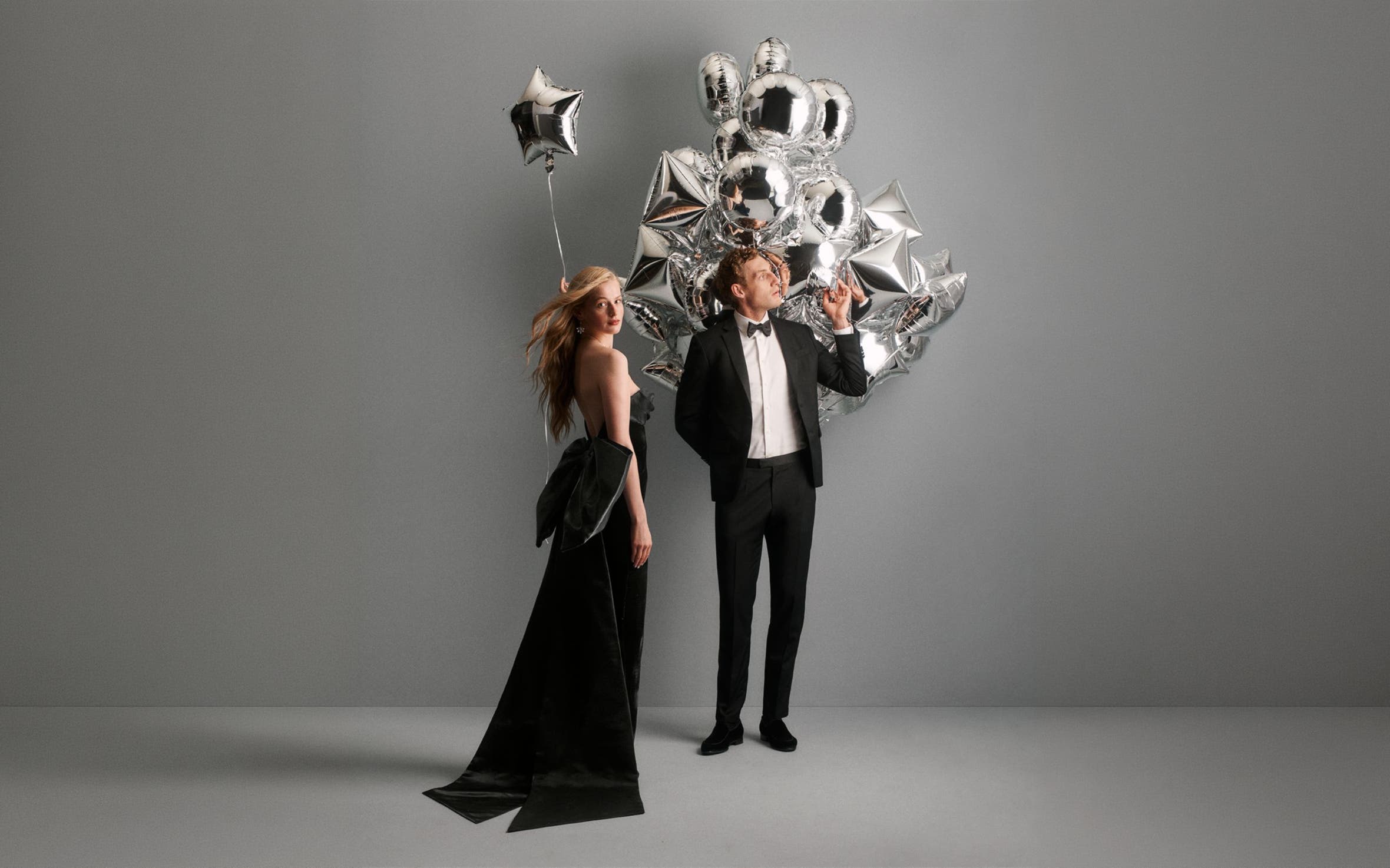 A woman and man in evening wear with balloons.