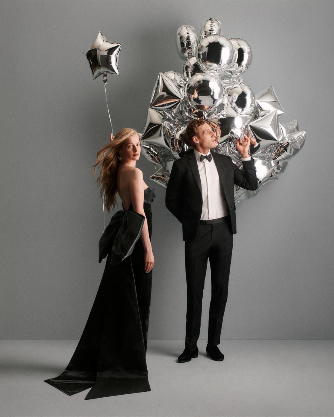 A couple standing next to balloons in holiday dressing.