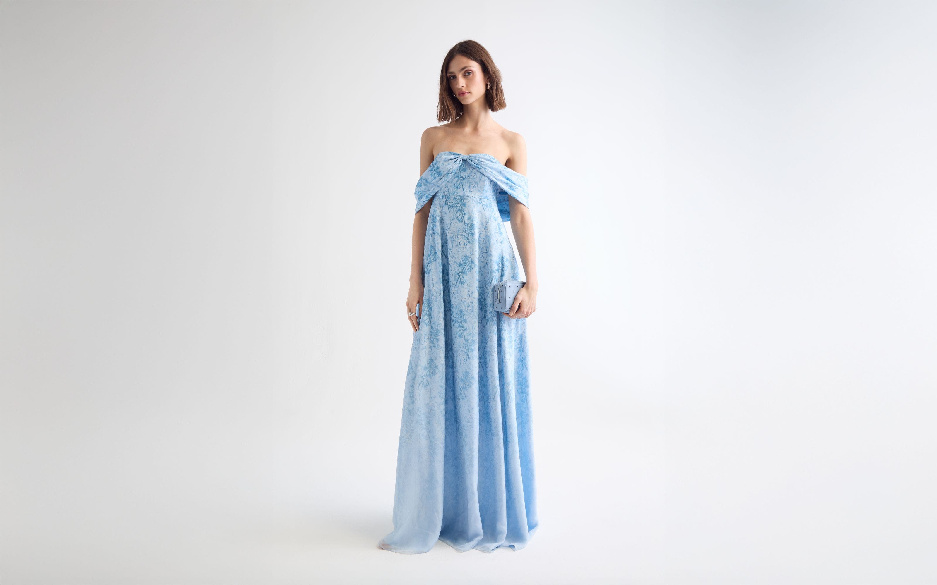 A woman wearing a floral-print off-the-shoulder gown.