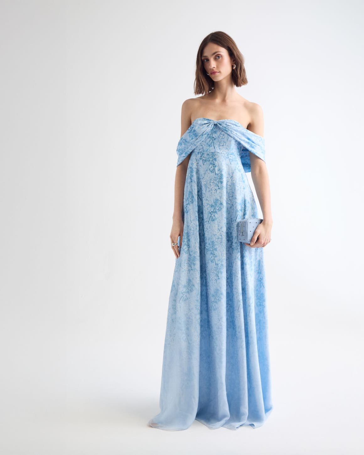 Woman wearing a blue floral evening gown and clutch.