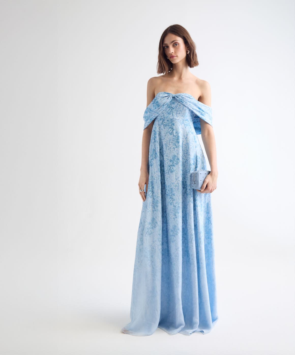 Woman wearing a blue floral evening gown and clutch.