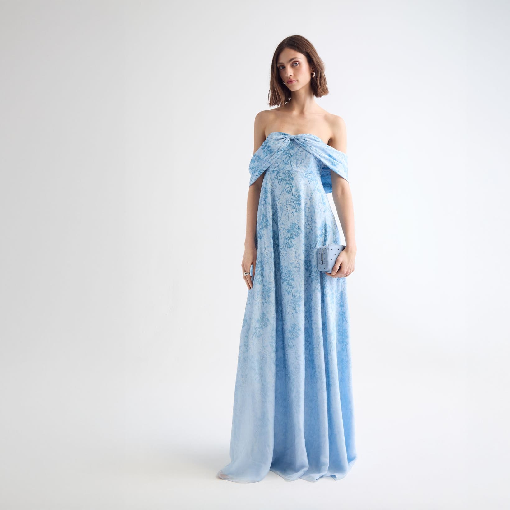 Woman wearing a blue floral evening gown and clutch.