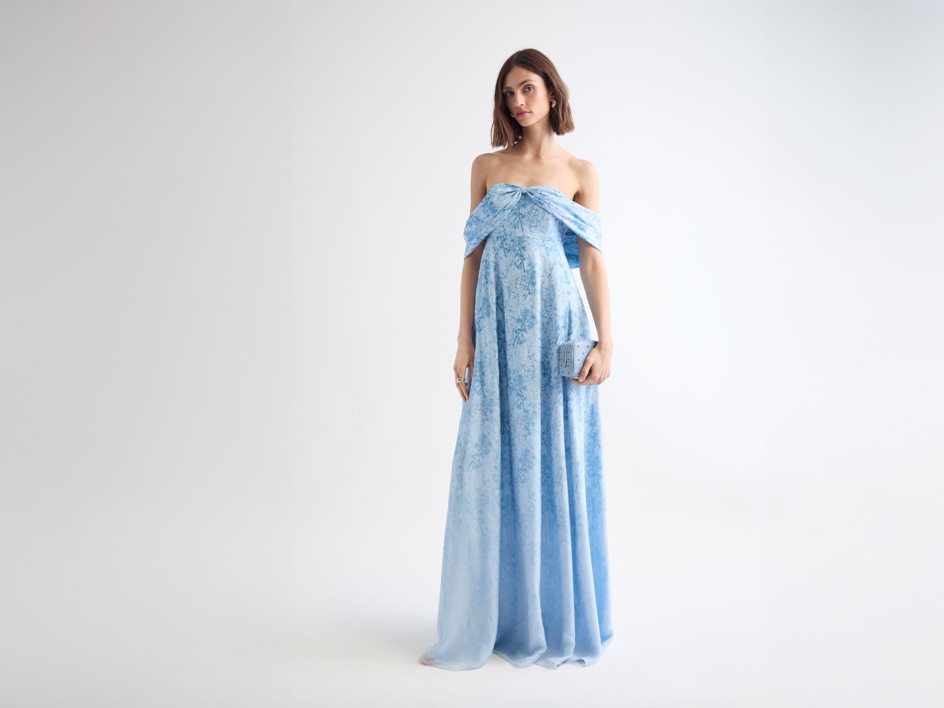 Woman wearing a blue floral evening gown and clutch.