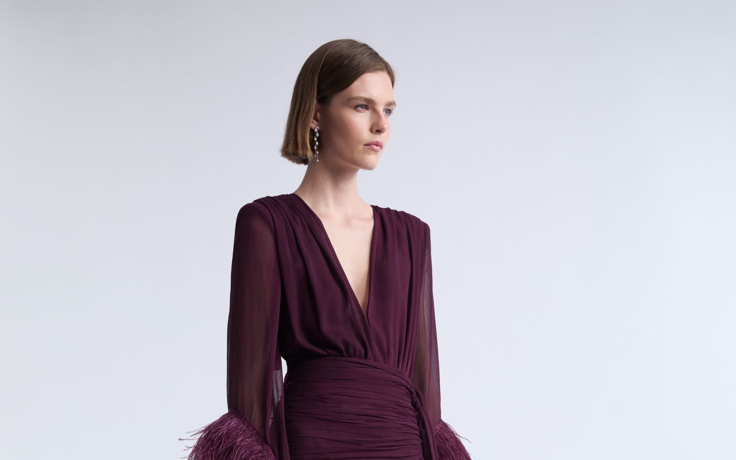 A woman wearing a burgundy gown with fringe.