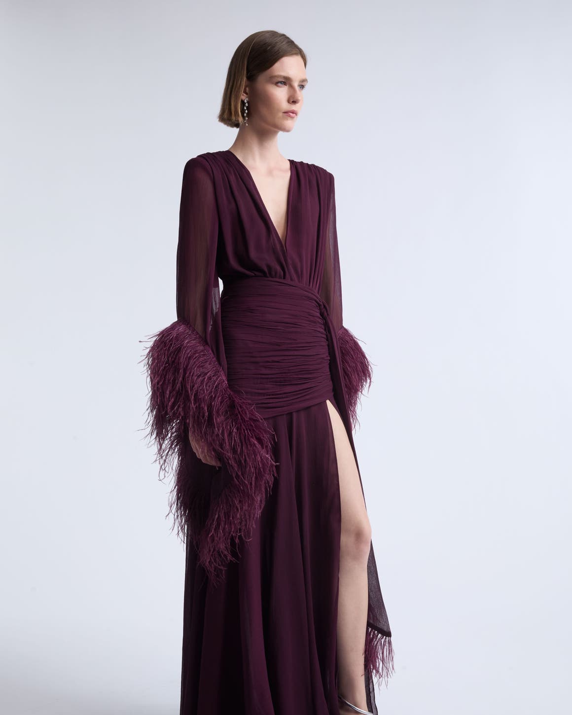 A woman wearing a burgundy gown with fringe.