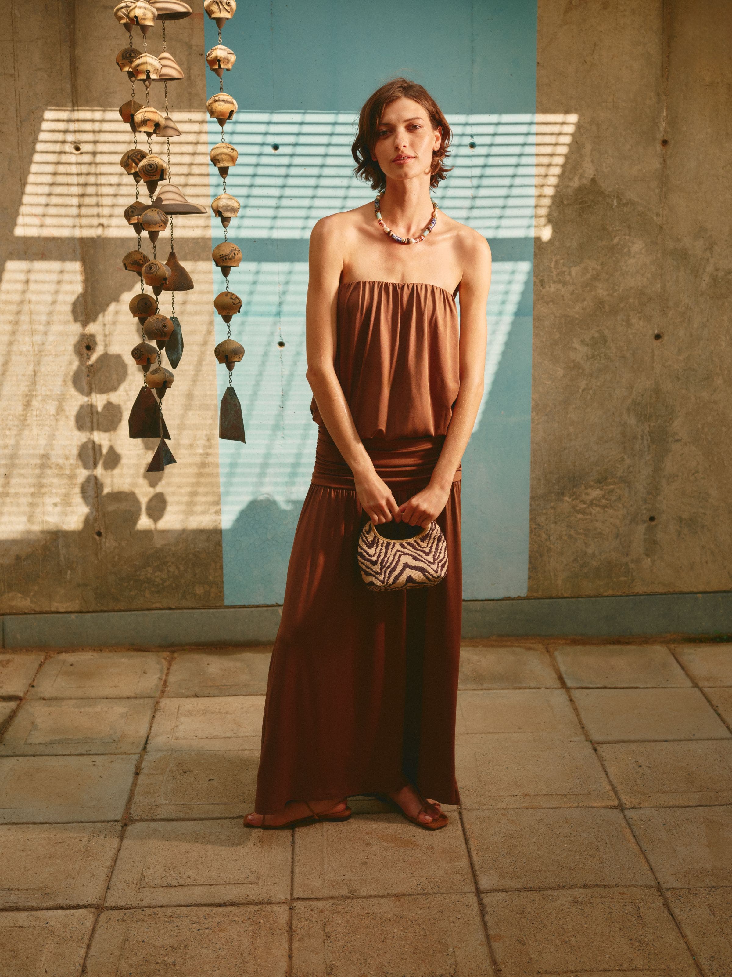 A woman holding a small woven bag with zebra stripes.