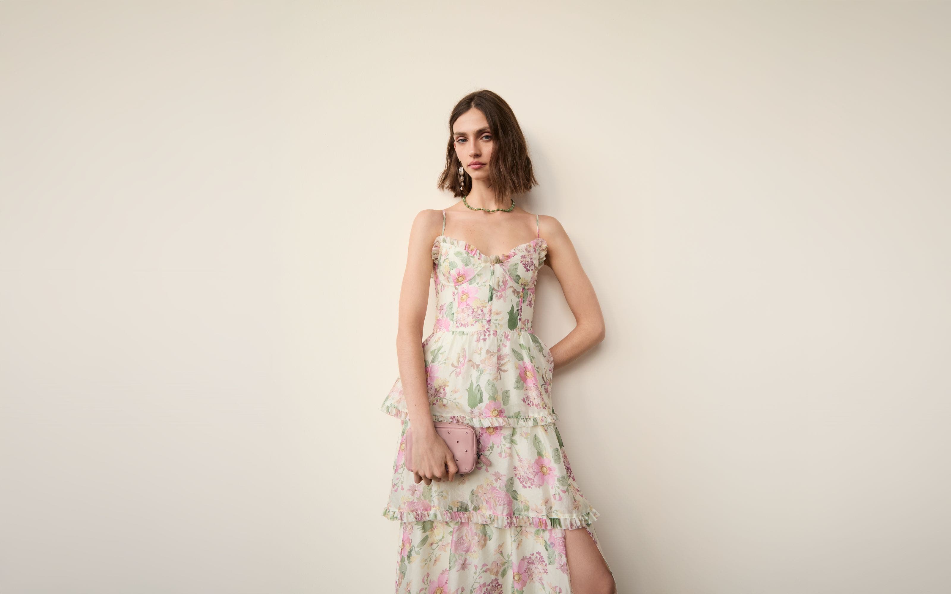 Woman wearing a tiered floral gown with accessories.