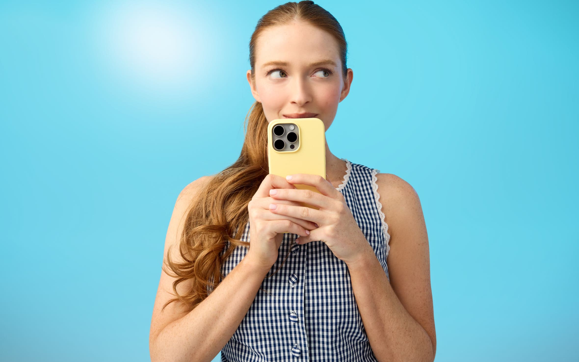 A woman wearing a green sweater and jeans and holding a phone.