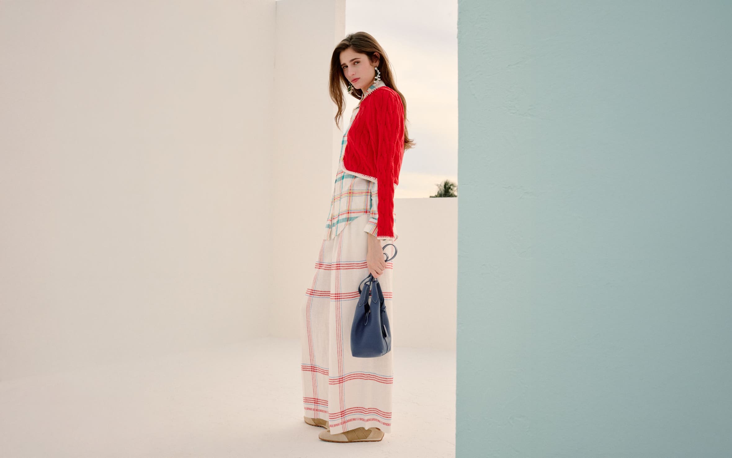 Woman wearing a red cardigan, striped shirt and plaid wide-leg pants.