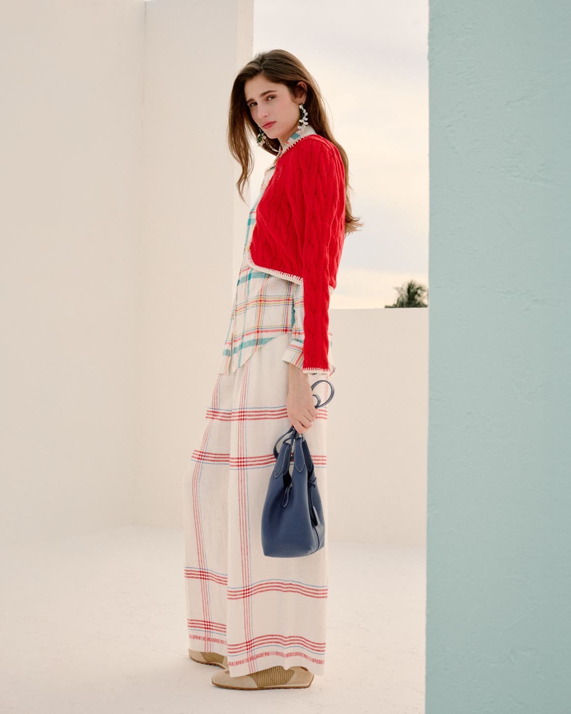 Woman wearing a red cardigan, striped shirt and plaid wide-leg pants.