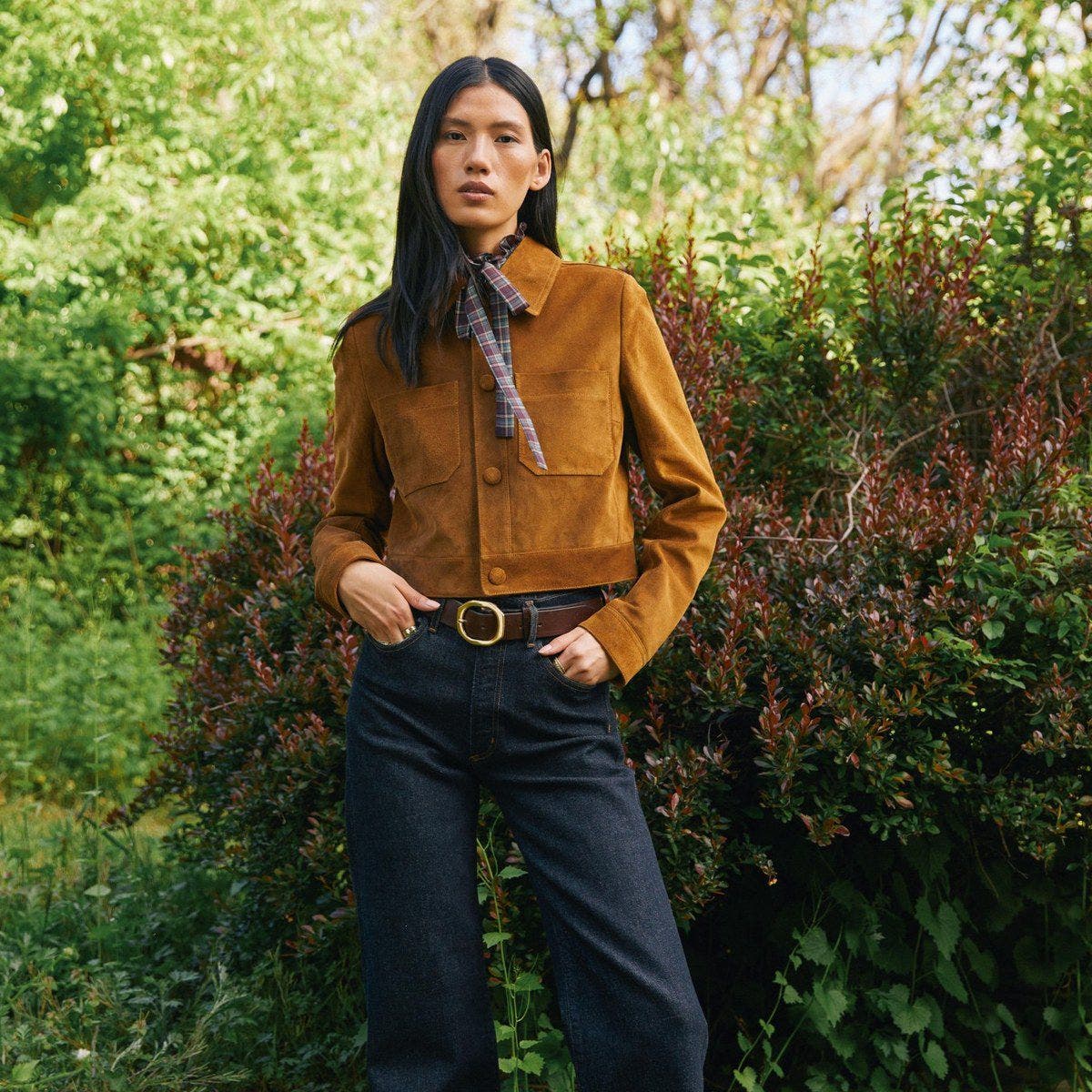 A woman in a tan suede jacket with a printed scarf.