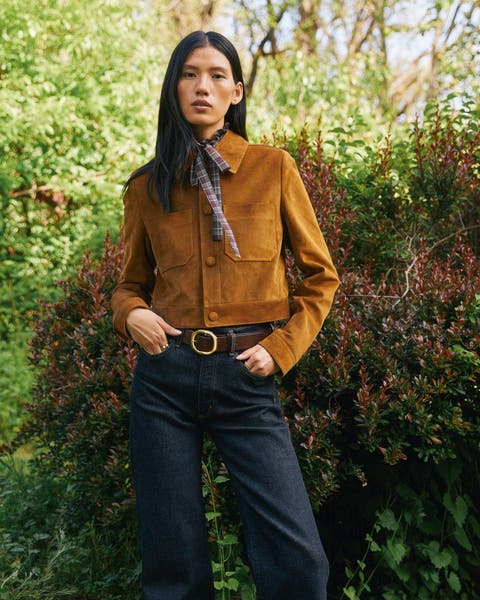 A woman in a tan suede jacket with a printed scarf.