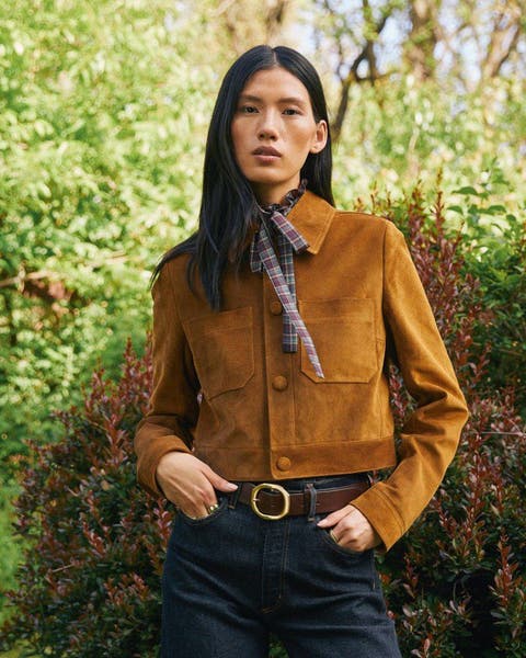 A woman in a tan suede jacket with a printed scarf.