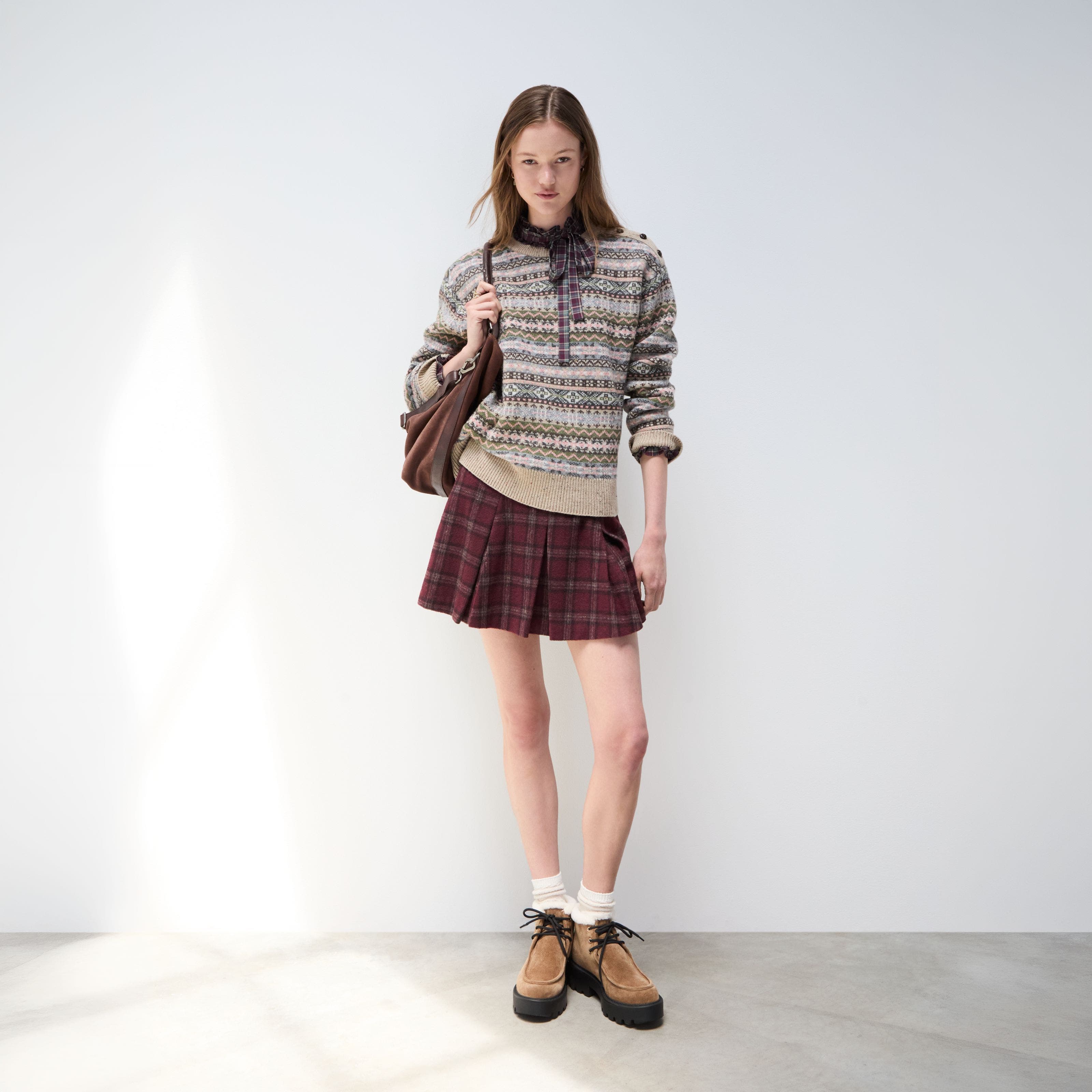 A woman wearing a Fair Isle sweater over a plaid dress.