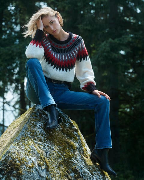 Woman wearing a sweater and denim jeans.