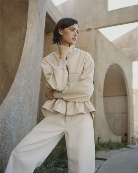 Woman wearing an off-white jacket and trousers.