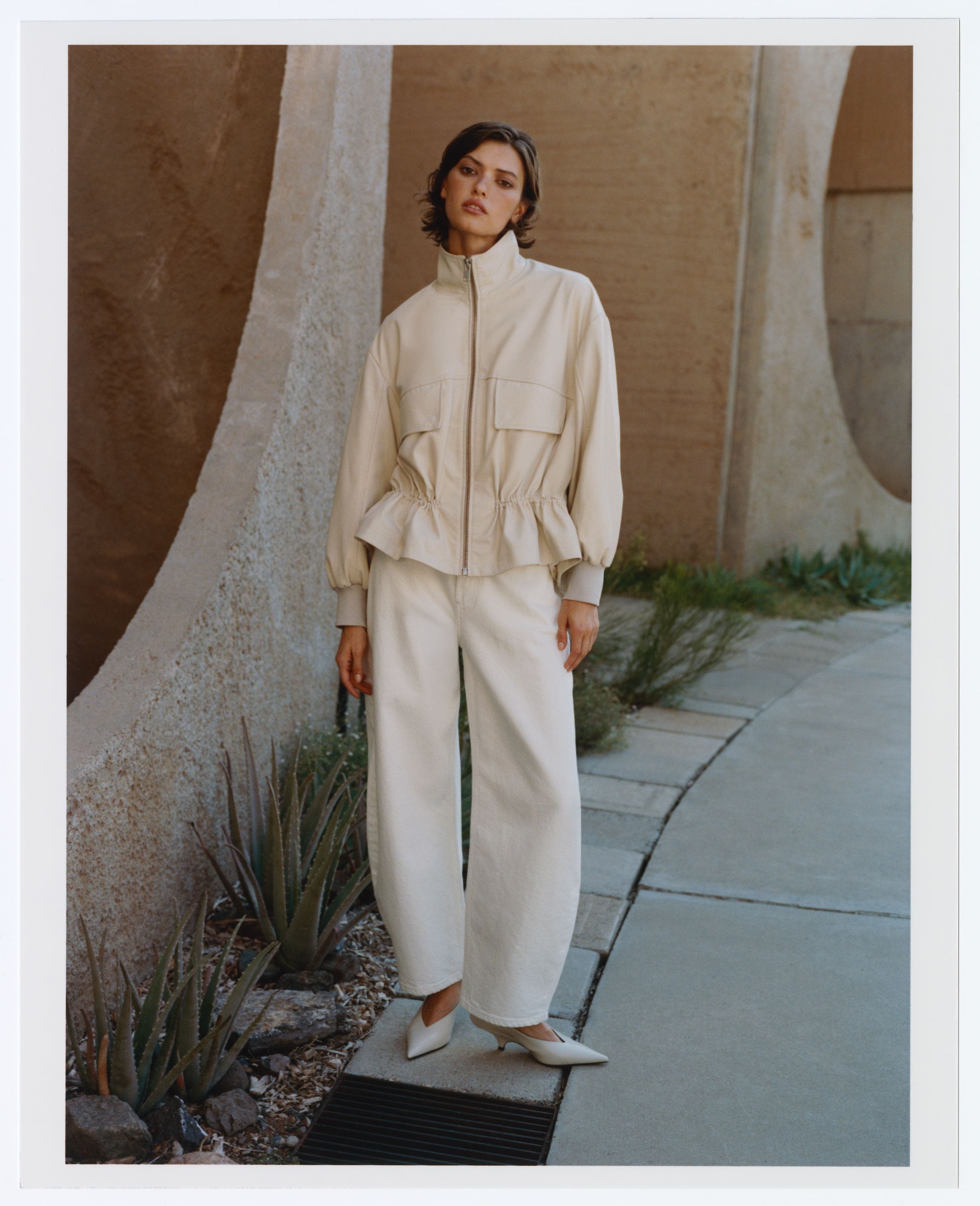 A woman wearing an off-white cinched-waist jacket.