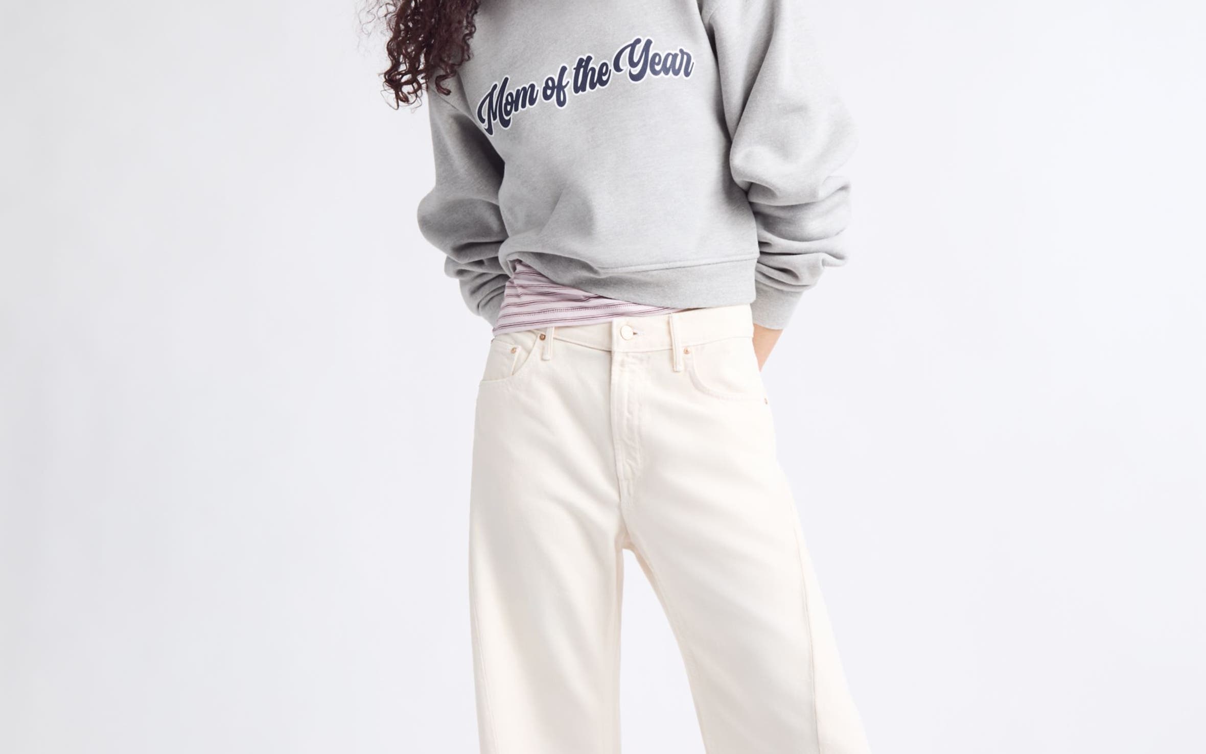 A woman wearing a "Mom of the Year" sweatshirt and wide-leg jeans.