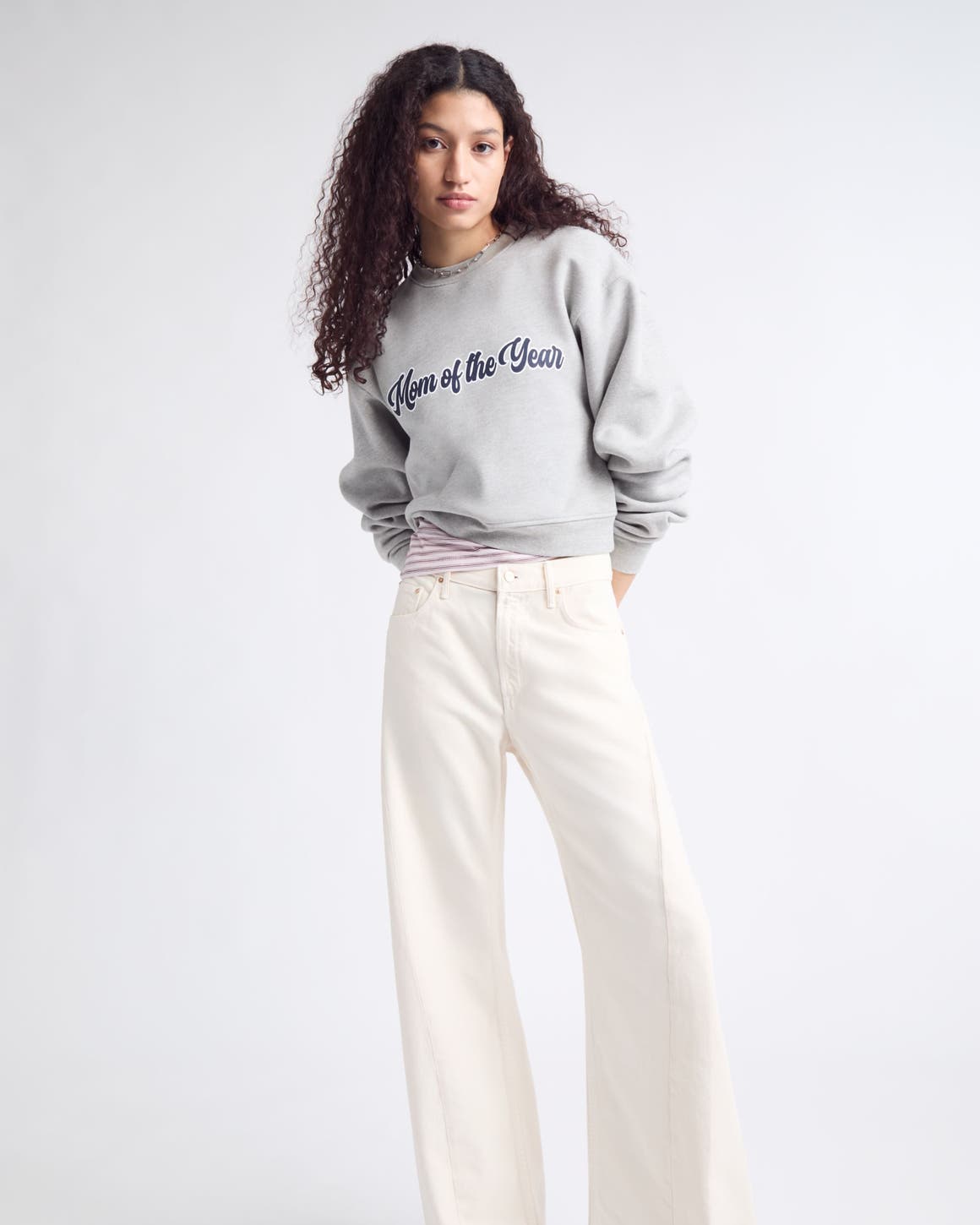 A woman wearing a "Mom of the Year" sweatshirt and wide-leg jeans.