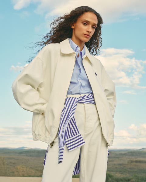 Woman wearing a matching jacket and pants with a blue button-up shirt.