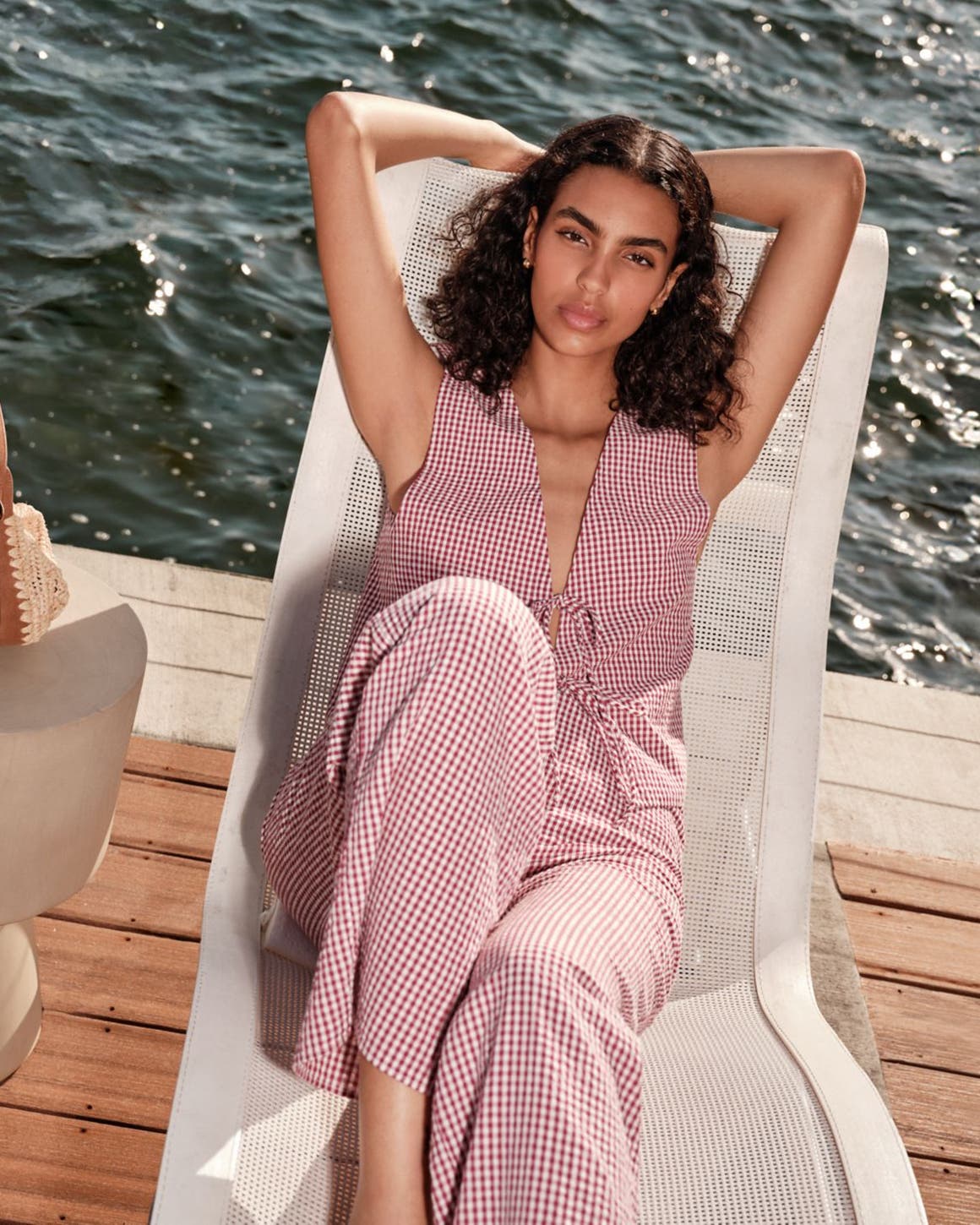 Woman sitting on a lounge chair, wearing a red stripe matching set.