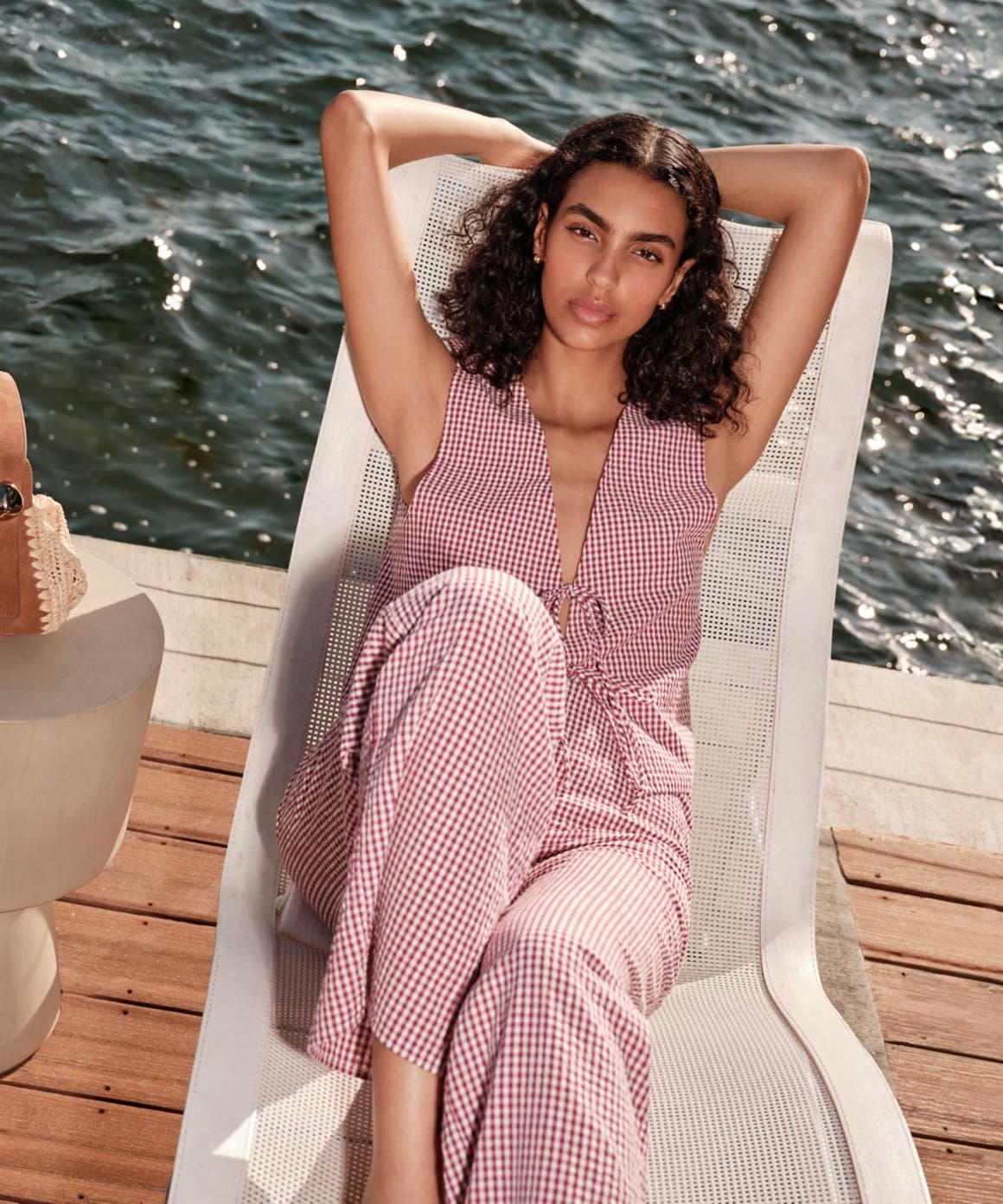 Woman sitting on a lounge chair, wearing a red stripe matching set.