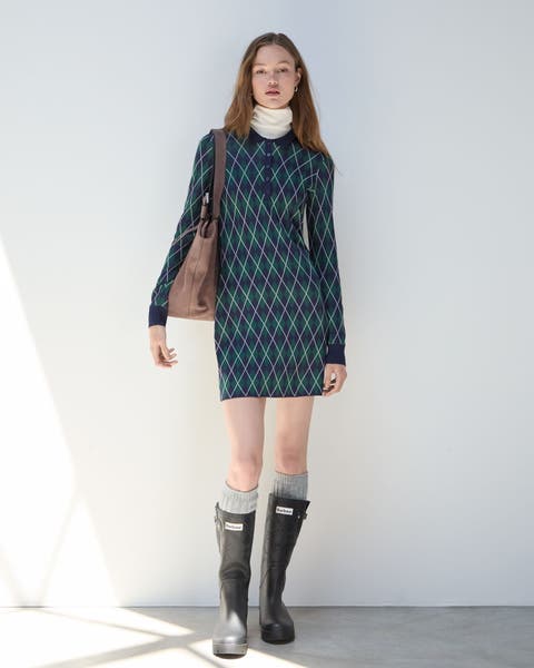 A woman wearing an argyle sweater dress and Hunter boots.